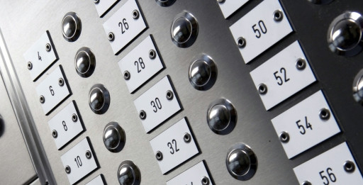 VvE nummerplaatjes op een RVS bellentableau